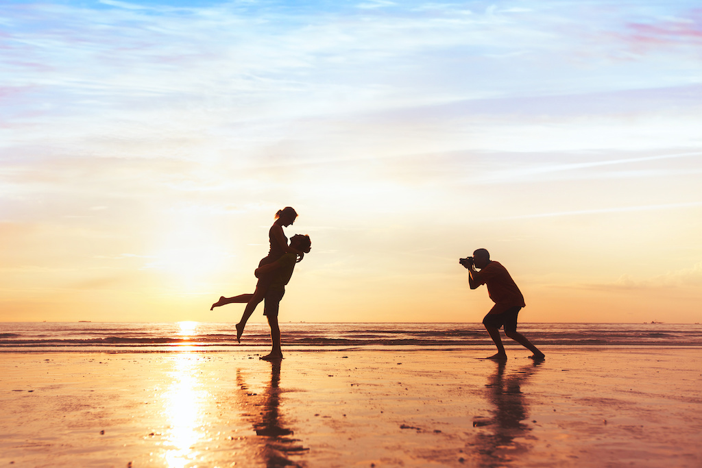 Professional photographer snapping couple's pre-wedding photos at sunset